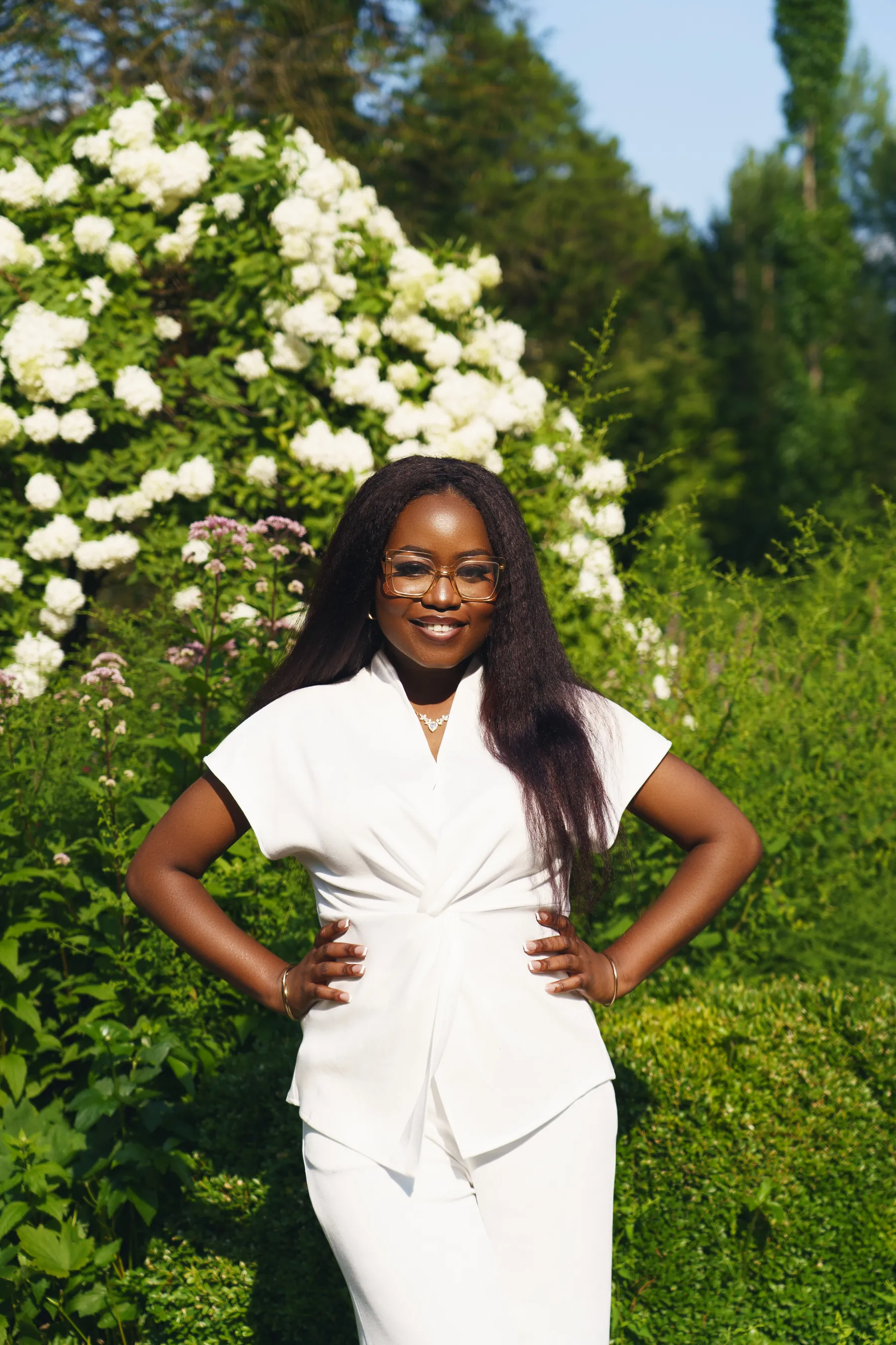 Gemima, founder of Gemistry Beauty, in white among garden hydrangeas